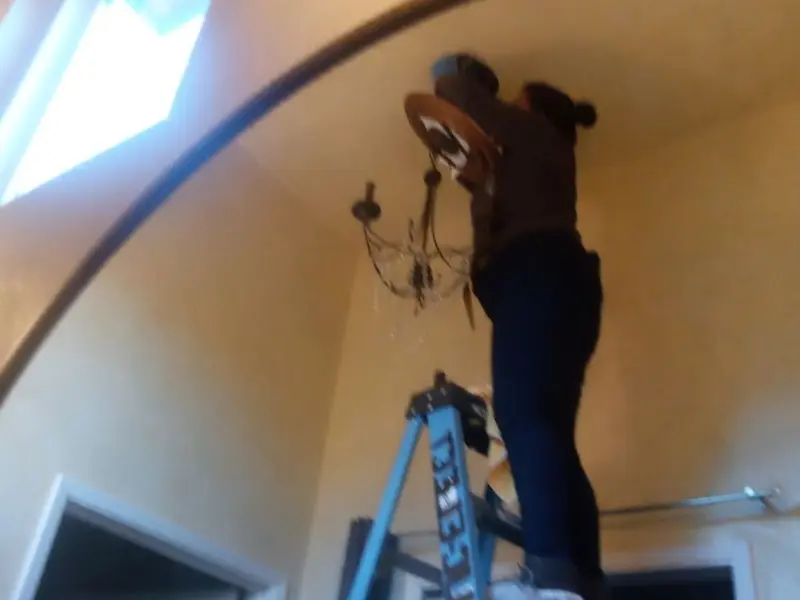 Electrician installing a chandelier in a Calabash residence